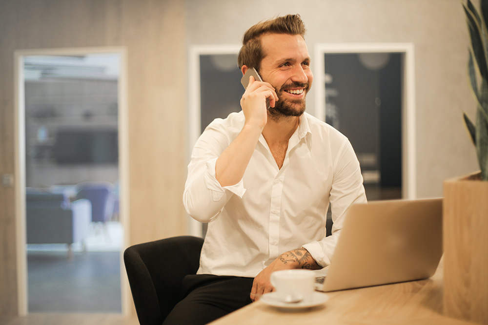 man at desk smiling on the phone